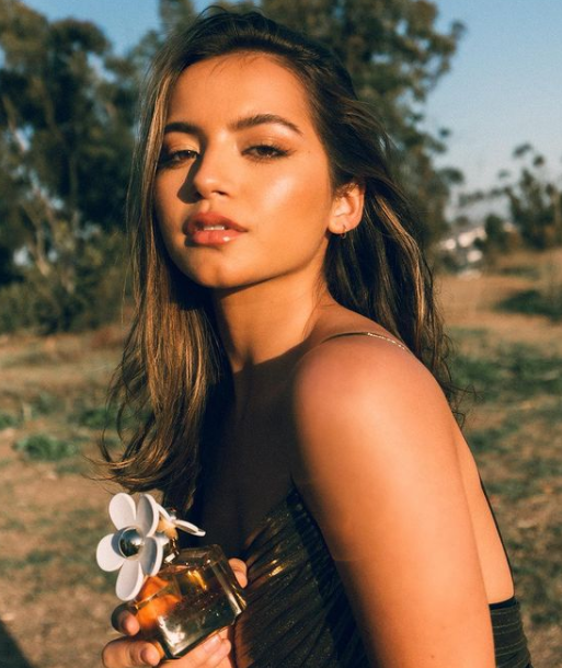 Isabela Moner holding a perfume bottle
